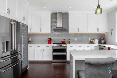 Mid-sized transitional u-shaped dark wood floor and brown floor eat-in kitchen photo in Seattle with a farmhouse sink, flat-panel cabinets, white cabinets, quartz countertops, gray backsplash, subway tile backsplash, stainless steel appliances, a peninsula and white countertops