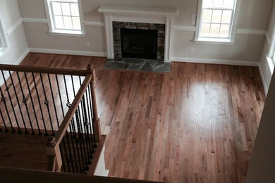 Family room - transitional light wood floor family room idea in Raleigh with white walls, a standard fireplace and a stone fireplace