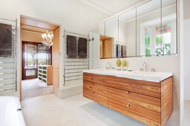 Inspiration for a large contemporary master bathroom in Sydney with an integrated sink, flat-panel cabinets, medium wood cabinets, white tile, white walls, limestone floors, a freestanding tub, an alcove shower, a wall-mount toilet and stone tile.
