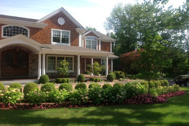 Photo of a large traditional partial sun front yard brick landscaping in New York.
