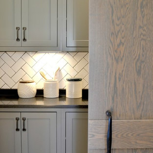 Large farmhouse kitchen pantry inspiration - Kitchen pantry - large cottage galley medium tone wood floor kitchen pantry idea in Indianapolis with a farmhouse sink, recessed-panel cabinets, gray cabinets, granite countertops, gray backsplash, subway tile backsplash, stainless steel appliances and an island