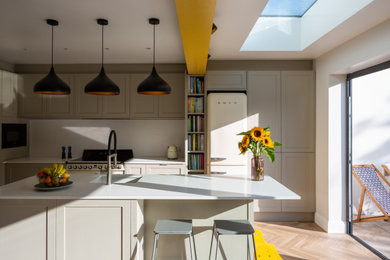 Design ideas for a medium sized modern grey and white single-wall kitchen/diner in Essex with a double-bowl sink, recessed-panel cabinets, grey cabinets, quartz worktops, white splashback, wood splashback, coloured appliances, vinyl flooring, an island, brown floors, white worktops, exposed beams and feature lighting.