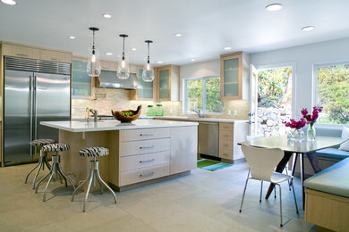 This is an example of a contemporary l-shaped kitchen in Los Angeles with flat-panel cabinets, stainless steel appliances, beige splashback, matchstick tile splashback and light wood cabinets.