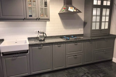 This is an example of a mid-sized contemporary l-shaped eat-in kitchen in Moscow with an integrated sink, glass-front cabinets, grey cabinets, granite benchtops, white splashback, ceramic splashback, stainless steel appliances, porcelain floors, no island, grey floor and grey benchtop.
