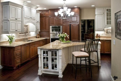 Example of a large classic l-shaped dark wood floor and brown floor eat-in kitchen design in Other with an undermount sink, beaded inset cabinets, medium tone wood cabinets, granite countertops, beige backsplash, stone tile backsplash, stainless steel appliances and an island