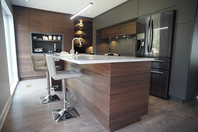 This is an example of a mid-sized modern l-shaped separate kitchen in Montreal with an undermount sink, stainless steel appliances, dark hardwood floors, brown floor, flat-panel cabinets, dark wood cabinets, solid surface benchtops and with island.