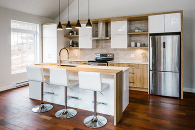 Example of a mid-sized trendy galley dark wood floor kitchen design in Montreal with a double-bowl sink, flat-panel cabinets, white cabinets, solid surface countertops, gray backsplash, ceramic backsplash, stainless steel appliances, an island and white countertops