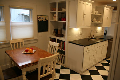 Example of a mid-sized classic l-shaped vinyl floor eat-in kitchen design in Columbus with an undermount sink, shaker cabinets, white cabinets, quartz countertops, white backsplash, ceramic backsplash, white appliances and no island