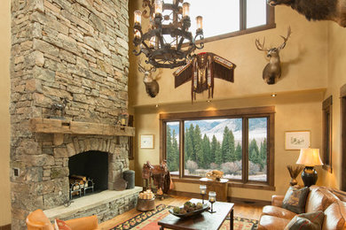 This is an example of an expansive country formal open concept living room in Other with beige walls, medium hardwood floors, a hanging fireplace, a stone fireplace surround, no tv and brown floor.