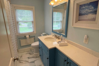 Example of a mid-sized transitional master white tile and porcelain tile porcelain tile, white floor and single-sink bathroom design in Boston with raised-panel cabinets, blue cabinets, a two-piece toilet, blue walls, an undermount sink, quartz countertops, white countertops and a built-in vanity