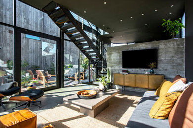 Example of a mid-sized urban enclosed concrete floor and gray floor family room design in Los Angeles with gray walls, no fireplace and a wall-mounted tv
