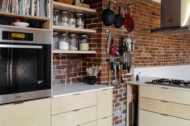 Enclosed kitchen - mid-sized contemporary u-shaped light wood floor and brown floor enclosed kitchen idea in Montreal with flat-panel cabinets, light wood cabinets, quartz countertops, red backsplash, brick backsplash, stainless steel appliances and white countertops