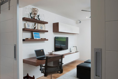 Example of a trendy light wood floor home office library design in Other with white walls
