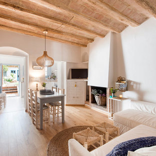 Foto de salón para visitas abierto, mediterráneo, de tamaño medio, con paredes blancas, suelo de madera en tonos medios, chimenea tradicional, marco de chimenea de ladrillo, pared multimedia y suelo marrón