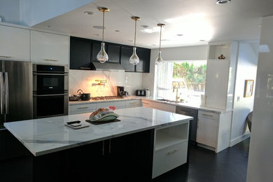 Large trendy l-shaped linoleum floor and black floor eat-in kitchen photo in Vancouver with an undermount sink, flat-panel cabinets, black cabinets, tile countertops, white backsplash, porcelain backsplash, stainless steel appliances, an island and white countertops