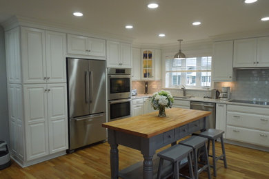Large elegant u-shaped light wood floor eat-in kitchen photo in Bridgeport with an undermount sink, raised-panel cabinets, white cabinets, marble countertops, white backsplash, subway tile backsplash, stainless steel appliances and an island