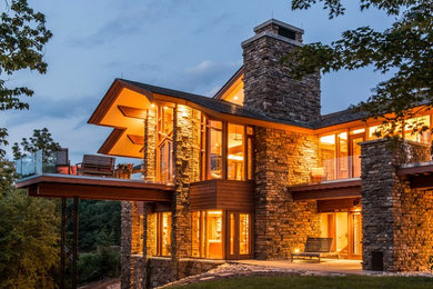 Large country two-storey brown house exterior in Other with stone veneer.