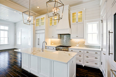 Example of a beach style dark wood floor and brown floor kitchen design in Houston with beaded inset cabinets, white cabinets, quartz countertops, ceramic backsplash and an island