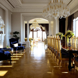 Cette image montre une grande salle à manger ouverte sur le salon traditionnelle avec un mur gris, un sol en bois brun, une cheminée standard et un manteau de cheminée en bois.