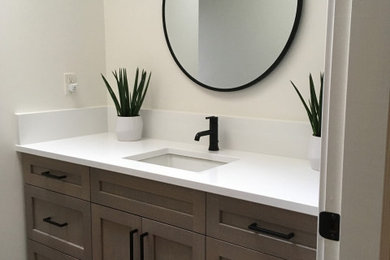 Photo of a mid-sized contemporary bathroom in Vancouver with flat-panel cabinets, medium wood cabinets, an alcove tub, a shower/bathtub combo, a one-piece toilet, white tile, white walls, ceramic floors, an undermount sink, engineered quartz benchtops, black floor, a sliding shower screen and white benchtops.