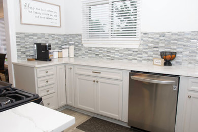 Example of a small mid-century modern galley vinyl floor and brown floor kitchen design in Detroit with a farmhouse sink, beige cabinets, quartz countertops, multicolored backsplash, ceramic backsplash, stainless steel appliances and beige countertops
