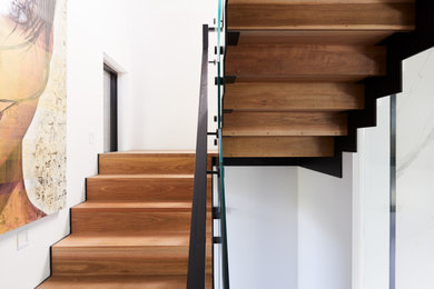 メルボルンにある広いインダストリアルスタイルのおしゃれな折り返し階段 (木の蹴込み板、金属の手すり) の写真