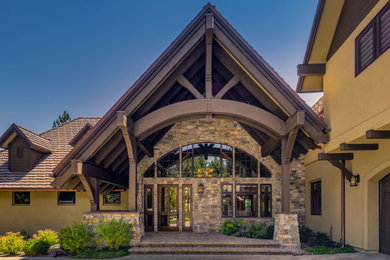 Inspiration for a large rustic beige two-story stucco exterior home remodel in Other with a tile roof