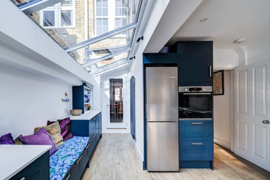 Design ideas for a contemporary kitchen in London with a submerged sink, shaker cabinets, blue cabinets, quartz worktops, stainless steel appliances, no island, brown floors and white worktops.