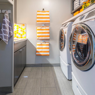 Photo of a small retro galley utility room in San Francisco with grey walls, porcelain flooring, a side by side washer and dryer, grey floors, a submerged sink, flat-panel cabinets, grey cabinets, engineered stone countertops and white worktops.
