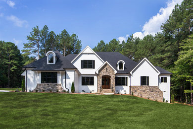 Immagine della villa grande bianca american style a due piani con tetto a padiglione, copertura a scandole e tetto nero
