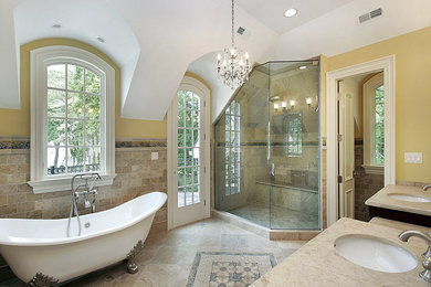 Inspiration for a large timeless master beige tile and stone tile porcelain tile and brown floor bathroom remodel in Los Angeles with yellow walls, an undermount sink, granite countertops and a hinged shower door