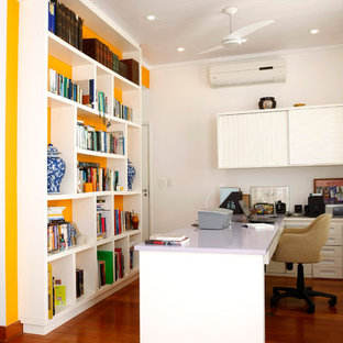 Photo of a modern home office and library in Other with yellow walls.