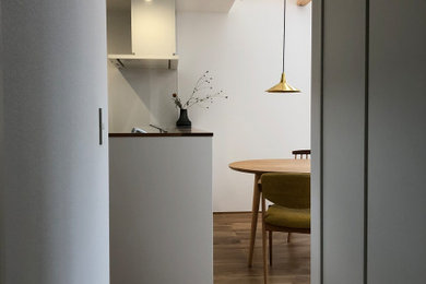 Foto di una piccola sala da pranzo aperta verso il soggiorno minimalista con pareti bianche, pavimento in legno massello medio, soffitto in carta da parati e carta da parati