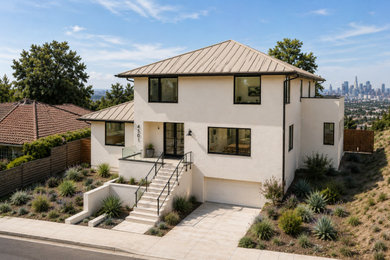 Inspiration for a large modern beige stucco house exterior remodel in Los Angeles with a metal roof