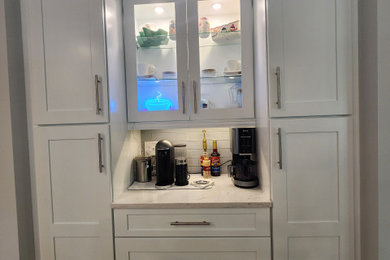 Example of a large classic light wood floor eat-in kitchen design in New York with an undermount sink, shaker cabinets, white cabinets, marble countertops, gray backsplash, glass tile backsplash, stainless steel appliances, an island and white countertops