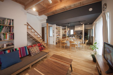 Kleines, Offenes Modernes Wohnzimmer mit weißer Wandfarbe, braunem Holzboden, freistehendem TV, freigelegten Dachbalken und Tapetenwänden in Sonstige