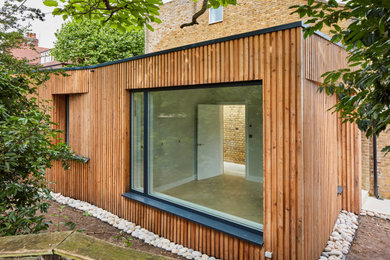 Small contemporary two floor rear semi-detached house in London with wood cladding, a flat roof, a green roof and board and batten cladding.
