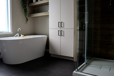 Design ideas for a mid-sized transitional master bathroom in Montreal with flat-panel cabinets, a freestanding tub, a corner shower, a two-piece toilet, brown tile, ceramic tile, beige walls, ceramic floors, a drop-in sink, laminate benchtops, black floor, a sliding shower screen, black benchtops, a single vanity and a built-in vanity.