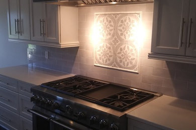 Inspiration for a large craftsman l-shaped dark wood floor and brown floor open concept kitchen remodel in Columbus with a farmhouse sink, shaker cabinets, white cabinets, quartz countertops, gray backsplash, subway tile backsplash, stainless steel appliances, an island and white countertops