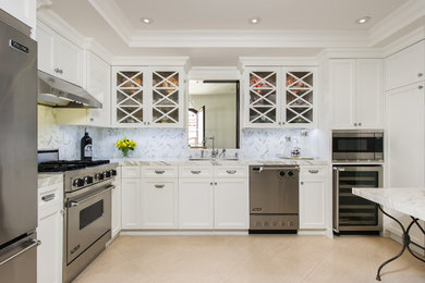 Example of a classic l-shaped kitchen design in Los Angeles with white backsplash and stone tile backsplash