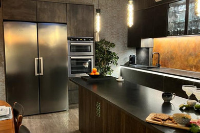 This is an example of a large contemporary kitchen in Essex with granite worktops, an island, black worktops, a vaulted ceiling and feature lighting.