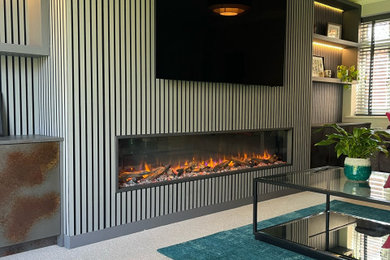 Photo of a large modern enclosed living room feature wall in Hampshire with grey walls, a wall mounted tv and panelled walls.