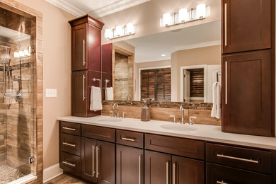 Inspiration for a mid-sized contemporary beige tile, brown tile and porcelain tile porcelain tile bathroom remodel in Other with recessed-panel cabinets, dark wood cabinets, a one-piece toilet, beige walls, an undermount sink and solid surface countertops