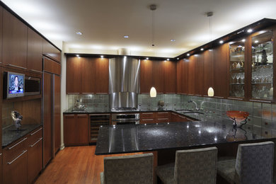 Inspiration for a mid-sized contemporary u-shaped medium tone wood floor and brown floor eat-in kitchen remodel in Chicago with a double-bowl sink, flat-panel cabinets, dark wood cabinets, quartz countertops, metallic backsplash, metal backsplash, paneled appliances and a peninsula