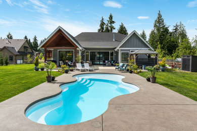 Example of a mid-sized transitional backyard concrete and custom-shaped natural pool landscaping design in Vancouver