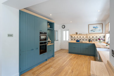 Immagine di una cucina design di medie dimensioni con lavello stile country, ante blu e top in legno