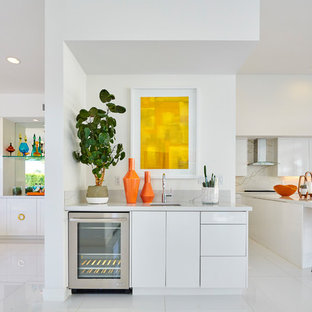 オレンジカウンティの小さいミッドセンチュリースタイルのおしゃれなウェットバー (フラットパネル扉のキャビネット、白いキャビネット、大理石カウンター、グレーのキッチンカウンター、アンダーカウンターシンク、白い床) の写真