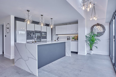 Large modern grey and white kitchen/diner in Other with white cabinets, quartz worktops, white splashback, an island, grey floors and white worktops.