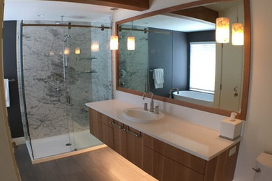 Mid-sized master bathroom in Vancouver with flat-panel cabinets, medium wood cabinets, a freestanding tub, an open shower, a two-piece toilet, grey walls, porcelain floors, an undermount sink, engineered quartz benchtops, grey floor, a sliding shower screen and white benchtops.