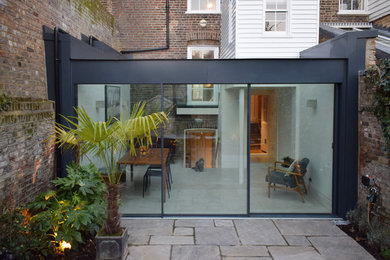 Mid-sized modern kitchen/dining combo in London with white walls, concrete floors and grey floor.